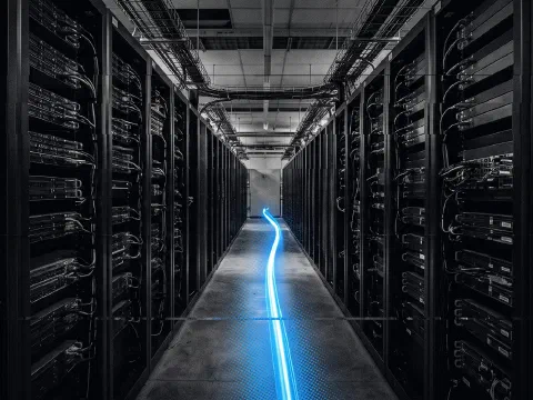 A black-and-white server aisle with a single blue streak of light running down the floor