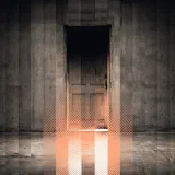 A tall wooden door in a concrete wall with a band of warm orange halftone light spilling from its lower gap